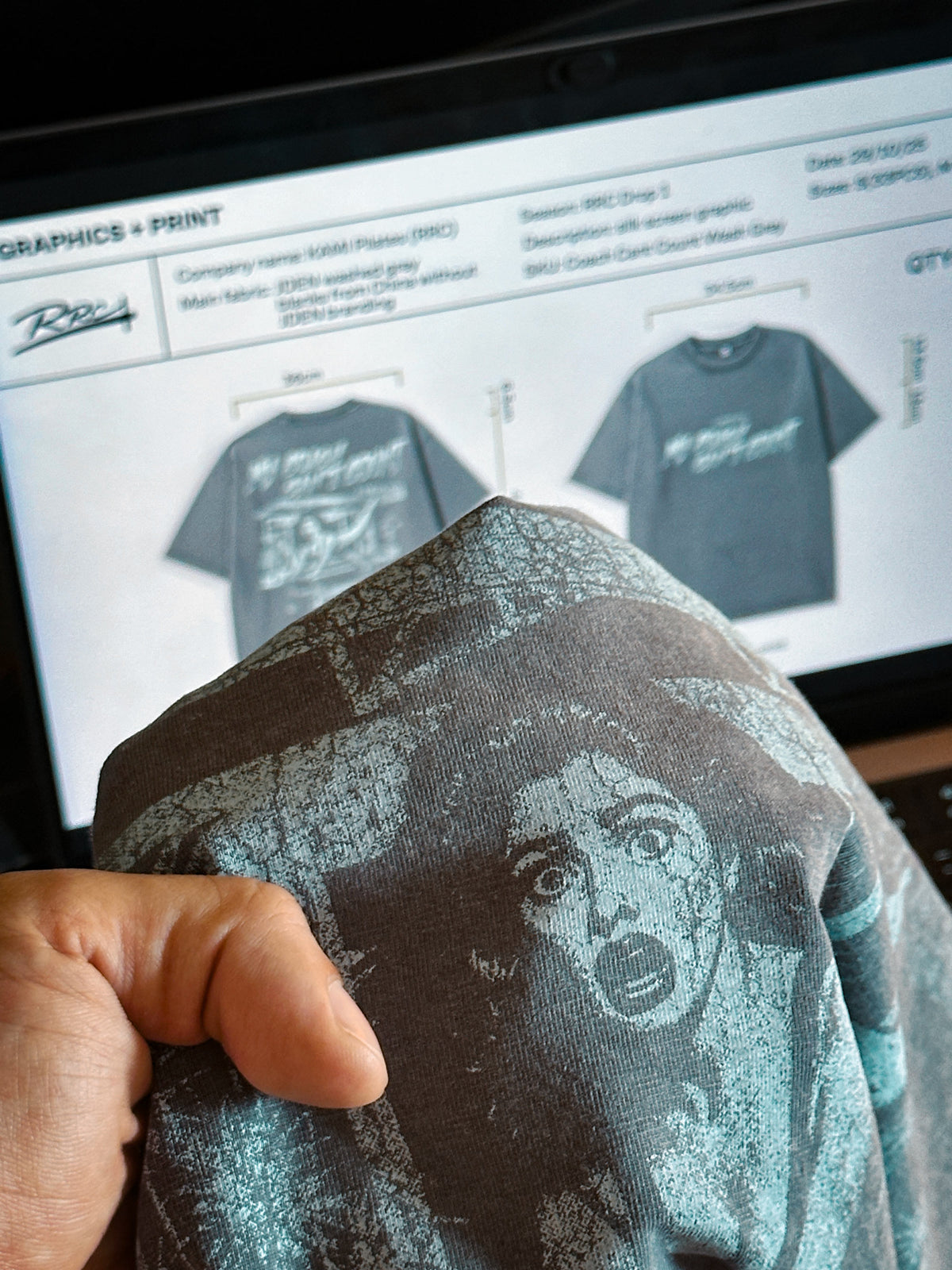 Person holding a printed fabric with graphics print design in front of a computer screen displaying similar designs.